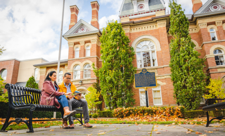 A couple sits on a bench in front of a courthouse